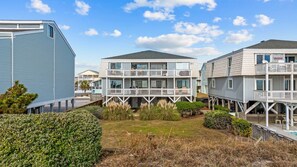 Un bien immobilier situé en bord de mer, composé de plusieurs bâtiments à étages dotés de balcons et d’espaces de détente en plein air.