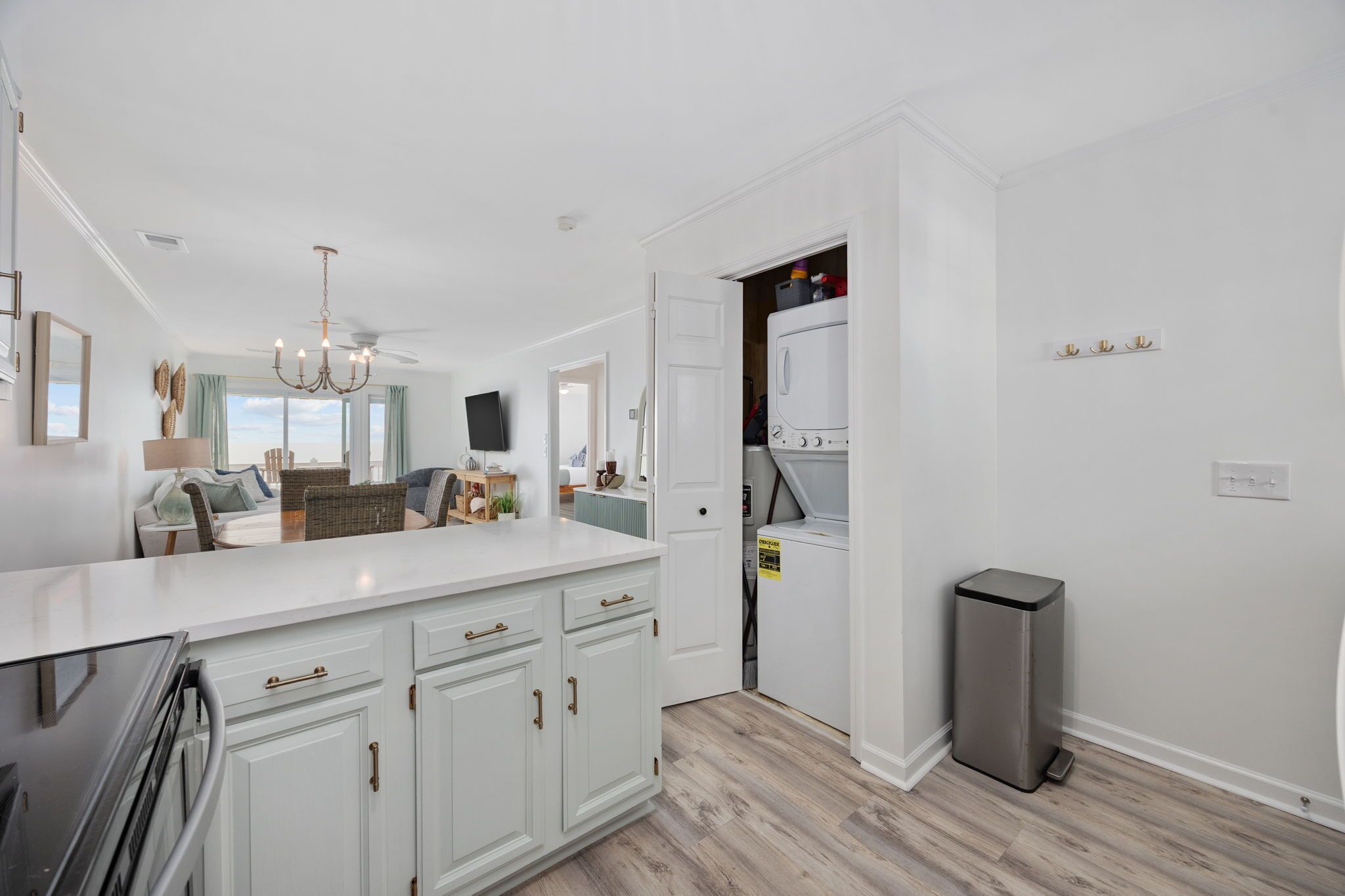 A modern kitchen with white cabinetry, a built-in oven, and a stainless steel trash can.