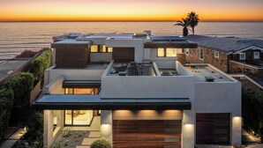 A modern house with a garage, solar panels, and a view of the ocean at sunset. - Luxury Coastal Escape w/ Resort-Style Amenities & Stunning Views (Del Mar)
