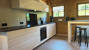 A modern kitchen with white cabinetry, a built-in oven, and a window with blinds. - Quiet vacation apartment 'Weideblick' in the middle of nature in Schluchsee-Blasiwald (Schluchsee)