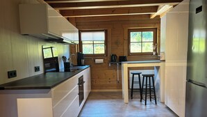 A modern kitchen with wooden beams, a central island with stools, and a stainless steel refrigerator. - Quiet vacation apartment 'Weideblick' in the middle of nature in Schluchsee-Blasiwald (Schluchsee)