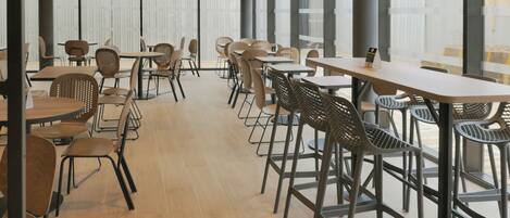 A spacious indoor dining area with high ceilings, large windows, and modern furniture.