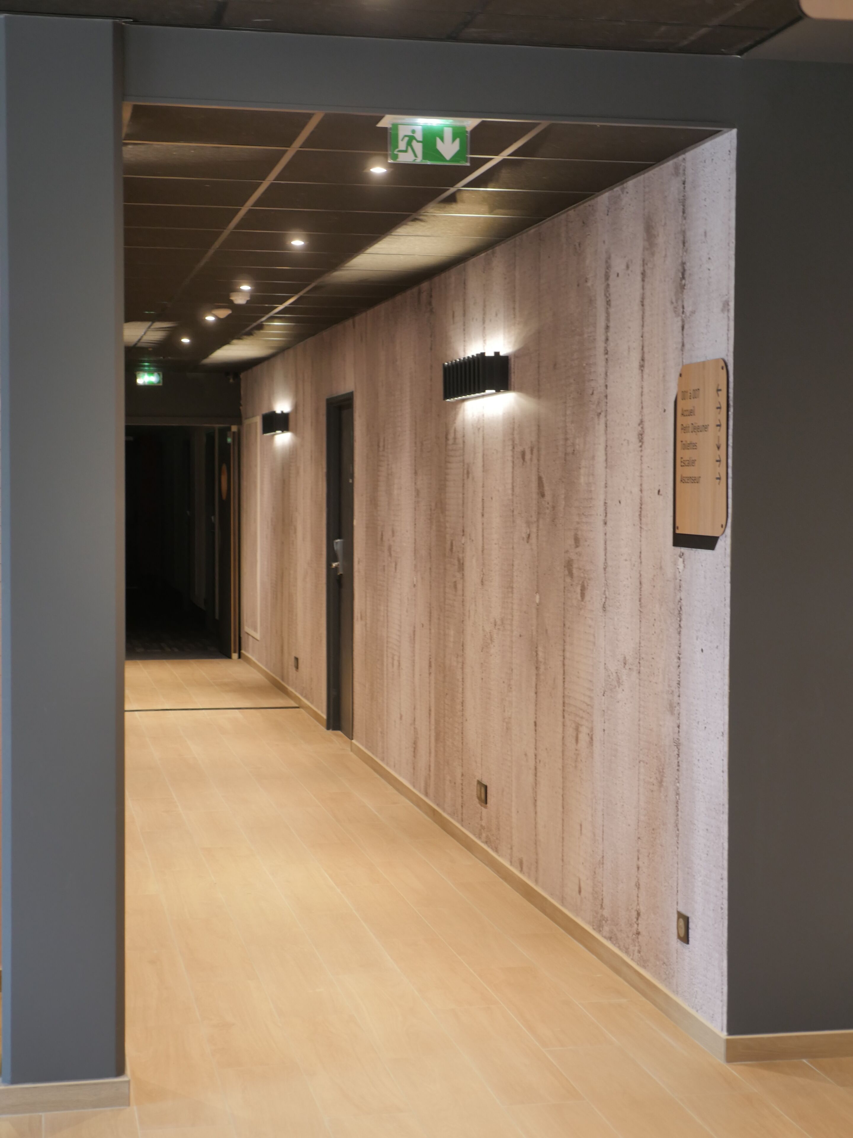 A hallway with wooden panel walls, a sign indicating a 2000-meter distance to the parking garage, and an emergency exit sign.