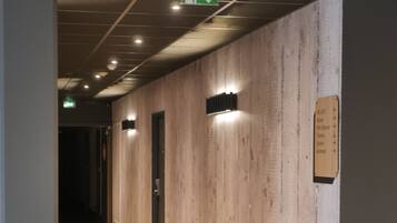 A hallway with wooden panel walls, a sign indicating a 2000-meter distance to the parking garage, and an emergency exit sign.
