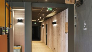 A hallway with a wooden wall, a door labeled "Escalier," and a sign indicating an exit. - BB HOTEL Carcassonne Rocadest La Cite (Carcassonne)