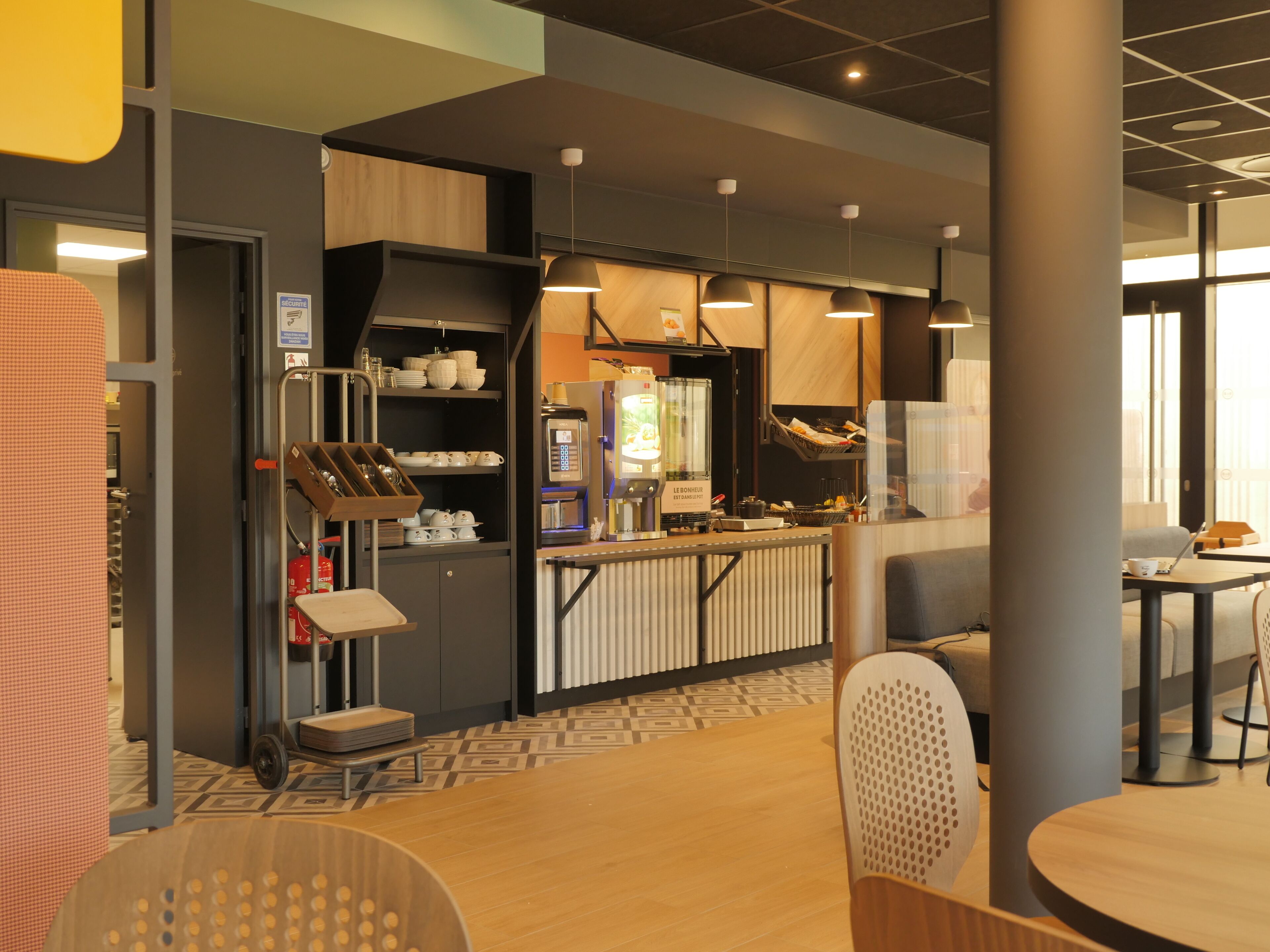 A modern cafe with a counter, seating area, and a coffee machine.
