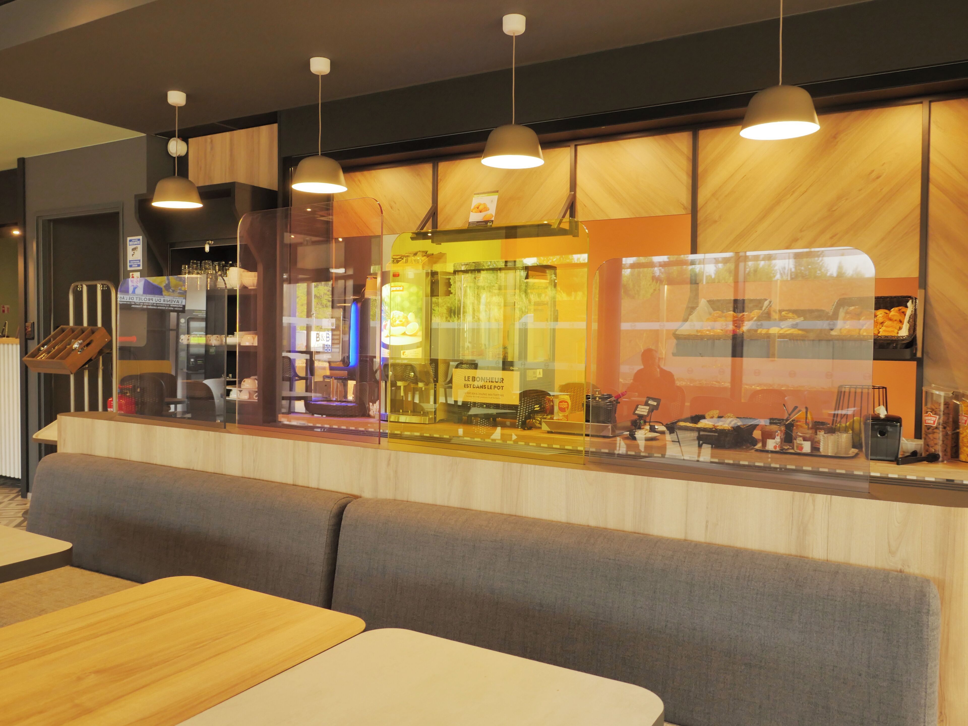 A modern restaurant with a wooden counter, seating area, and pendant lighting.