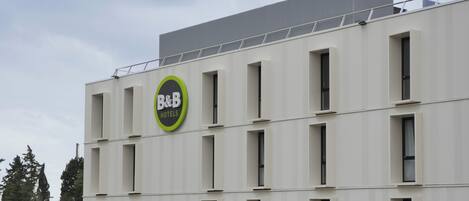 A modern B&B hotel building with a flat facade, multiple windows, and a rooftop terrace.