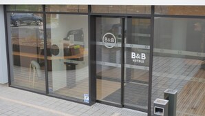A B&B hotel entrance with large glass doors, a visible trash bin, and a paved walkway. - BB HOTEL Carcassonne Rocadest La Cite (Carcassonne)