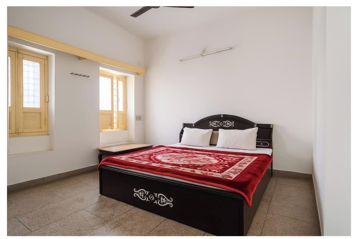A bedroom with a bed, a window, and a ceiling fan.