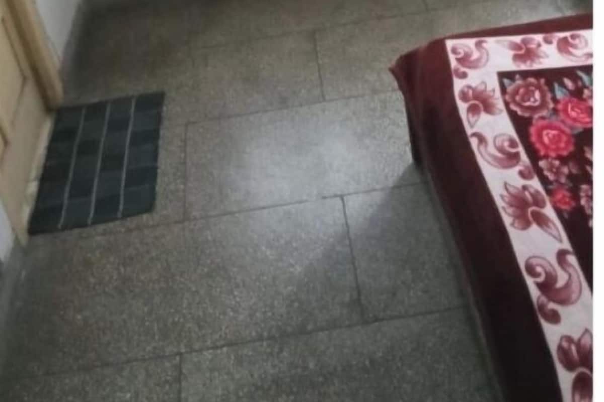 A room with a window, a radiator, a tiled floor, and a bed with a floral bedspread.