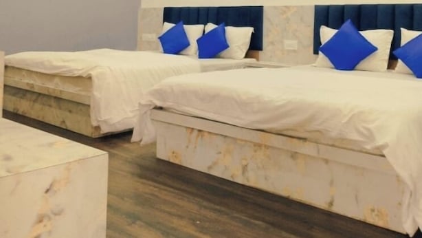 A hotel room with two beds, marble flooring, and a ceiling fan. - Devdarshan Hotel And Restaurant (Udaipur)
