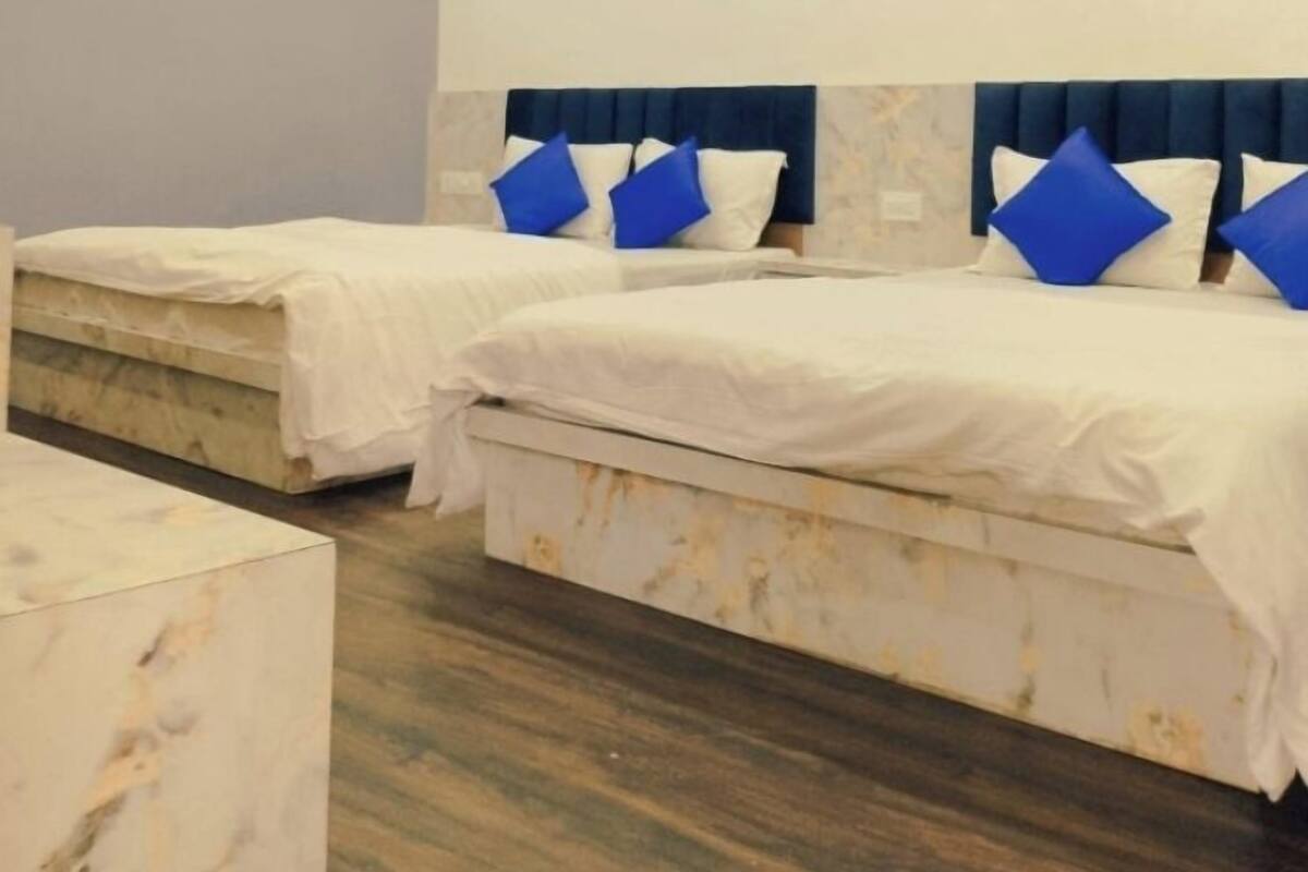 A hotel room with two beds, marble flooring, and a ceiling fan.