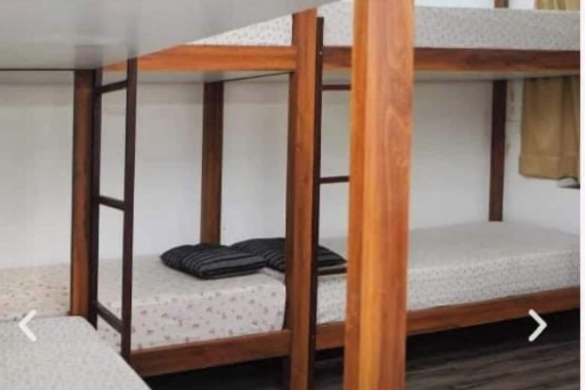 A bunk bed with a wooden frame and a mattress with a patterned cover.
