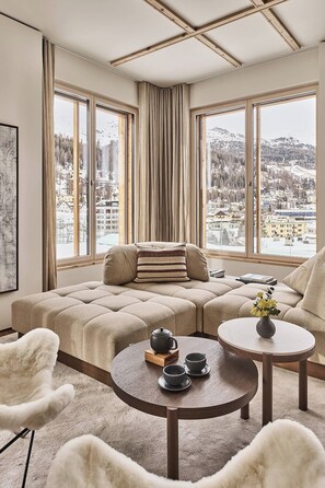 A modern living room with a sofa, two round tables, and a view of a snowy landscape through large windows.