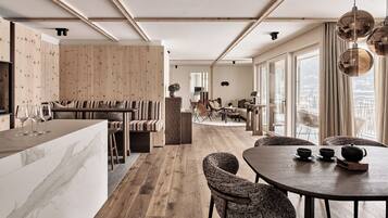 Una cocina moderna con armarios de madera, encimera de mármol y comedor con una mesa redonda y sillas de mimbre.