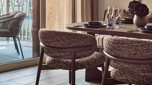 Un comedor con una mesa de madera, sillas tejidas y vistas a un paisaje nevado a través de amplios ventanales.