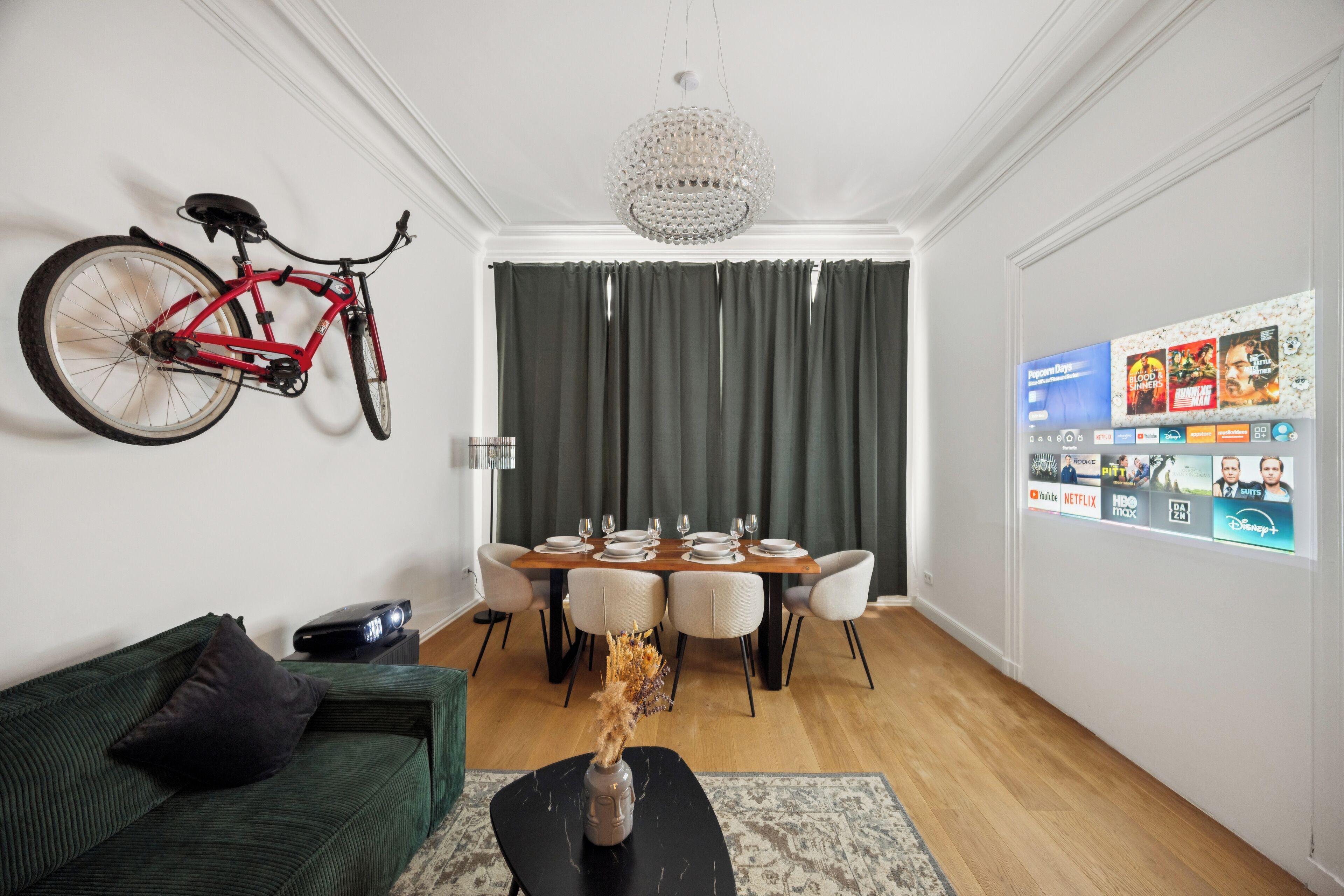 Un coin repas avec une table en bois dressée pour quatre personnes, un lustre et un vélo accroché au mur.