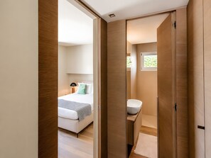Een moderne hotelkamer met een bed, nachtkastje, lamp en uitzicht op de badkamer.