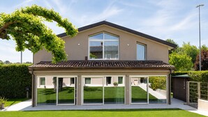 Une maison moderne dotée d’un patio couvert, d’une grande fenêtre et d’une pelouse bien entretenue.