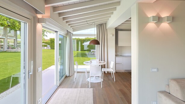 Un intérieur moderne comprenant un coin repas, des portes-fenêtres coulissantes donnant sur un jardin et une cuisine.