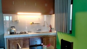 A compact kitchen with wooden cabinets, a gas stove, and a sink. There is a dining table with chairs and a vase with flowers.