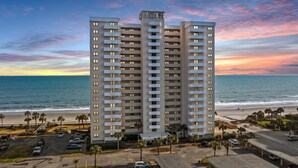 Un grand hôtel à plusieurs étages, doté d’un parking et offrant une vue sur la plage et l’océan.