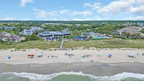 A beach resort with multiple buildings, a pier, and a sandy beach with umbrellas and people. - Oceans Rest Private Pool, luxury living in DeBordieu 7 bedrooms (Georgetown)
