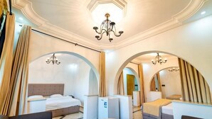 Hotellihuone, jossa on kaksi sänkyä, ruokapöytä ja kattokruunu.