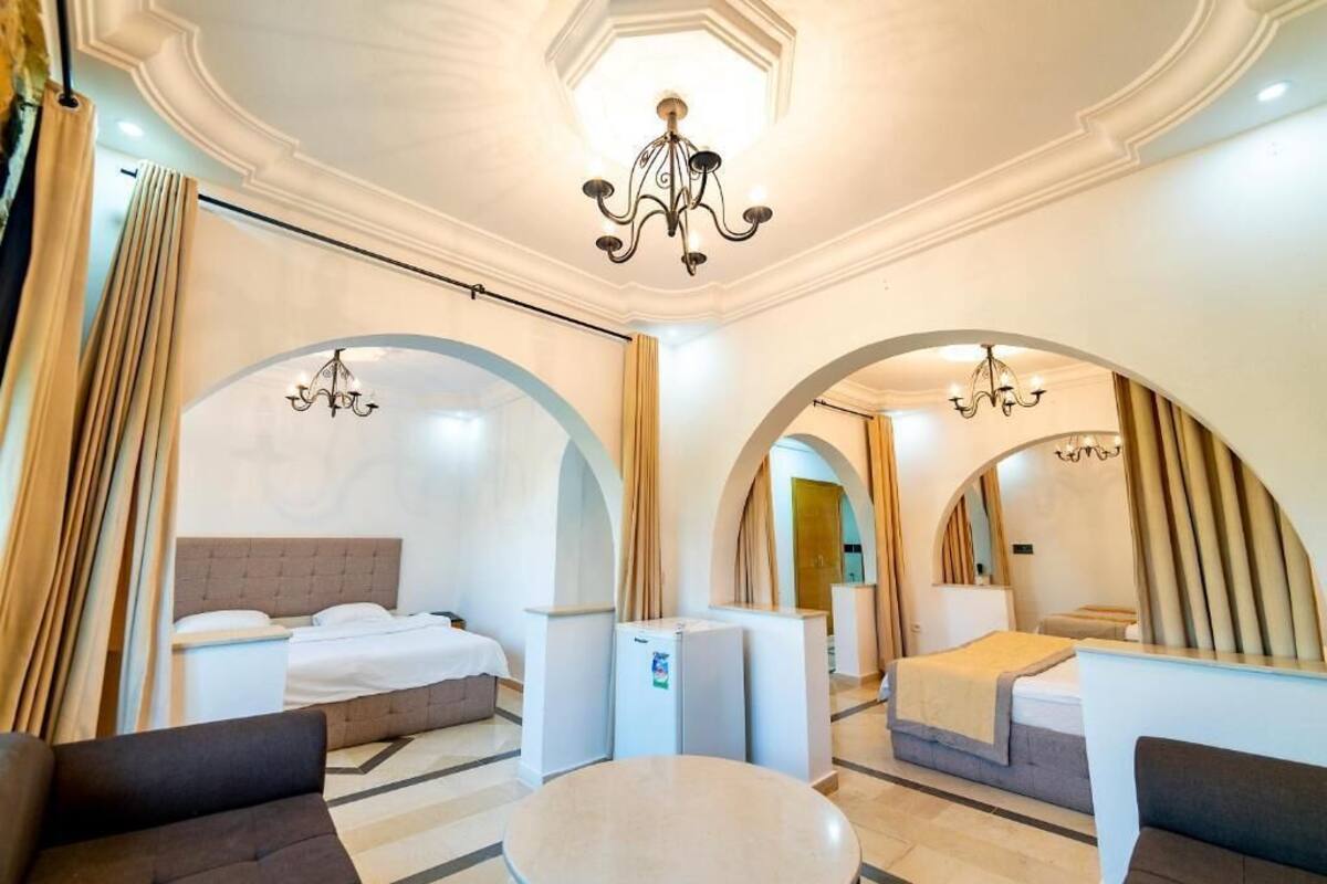 Ein Hotelzimmer mit zwei Betten, einem Esstisch und einer Chandelüstere.