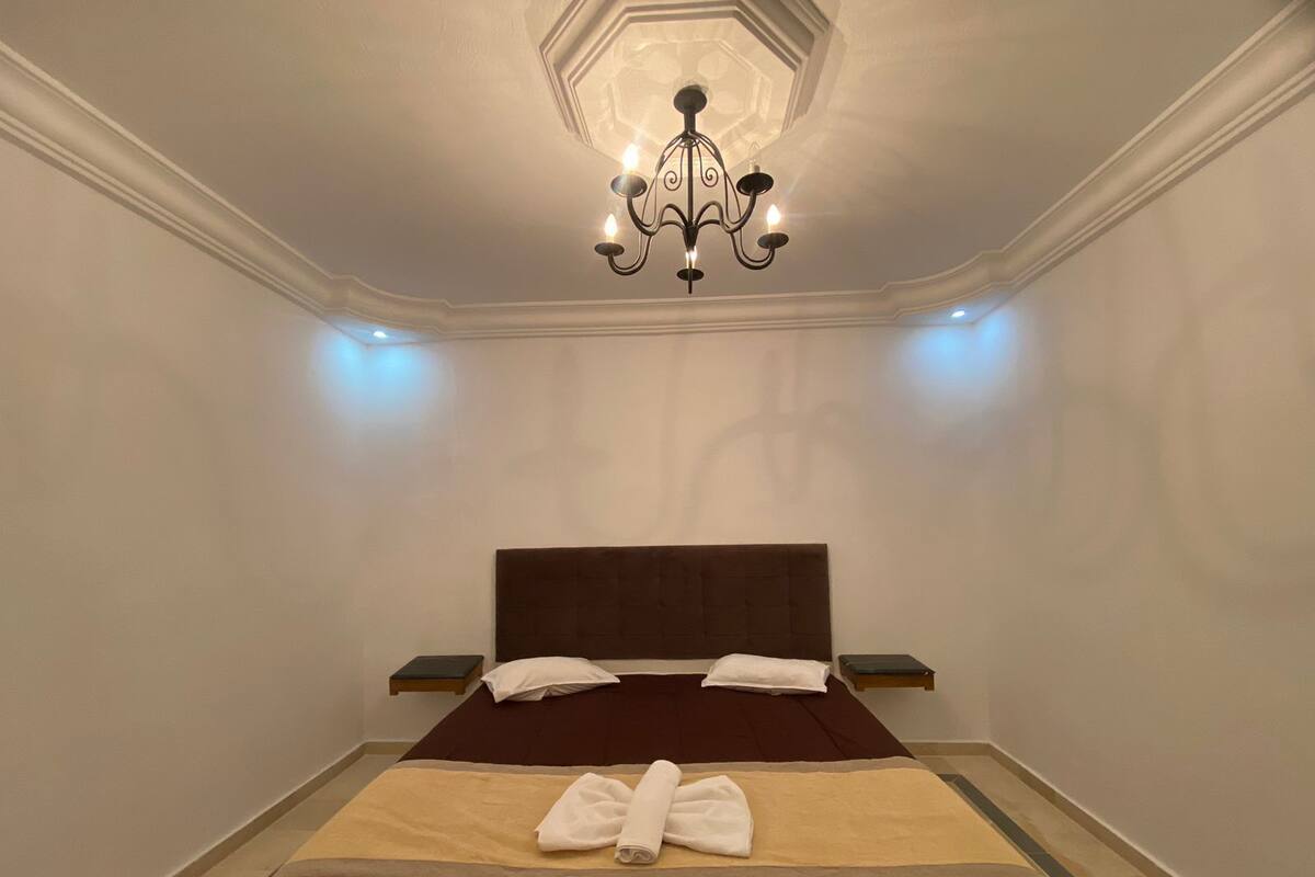 Ein Hotelzimmer mit einem großen Bett, einem Kronleuchter und Nachttischen.
