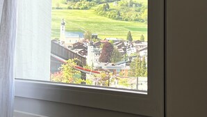 Uitzicht vanuit een raam op een bergachtig landschap met een dorp beneden.