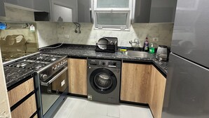 Eine kompakte Küche mit einem Gaskochfeld, einer eingebauten Waschmaschine und einem Edelstahlkühlschrank.