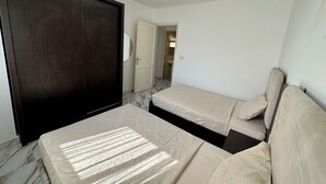 Ein Schlafzimmer mit einem dunklen Holzschrank, einem Bett mit einem gemusterten Überwurf und einer weißen Tür zu einem Badezimmer.