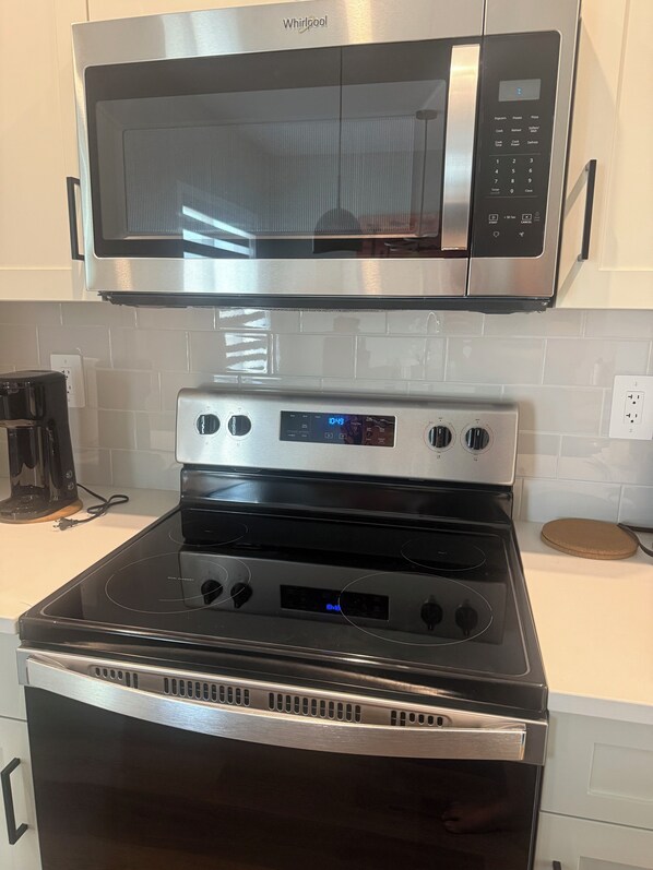 Una cocina con un microondas de acero inoxidable, un horno digital y una cafetera.