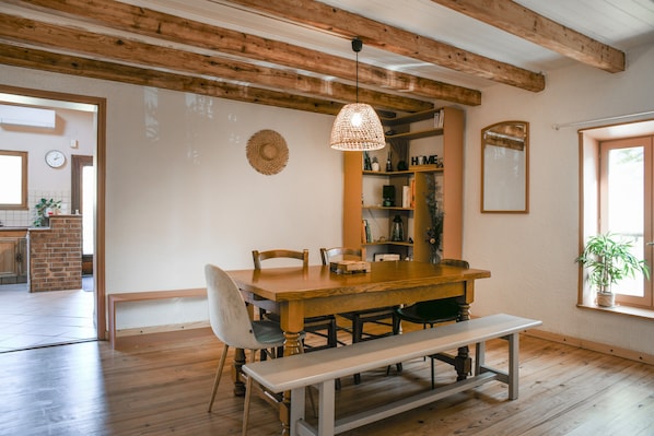 Un comedor con una mesa de madera, sillas, un banco y una lámpara colgante.