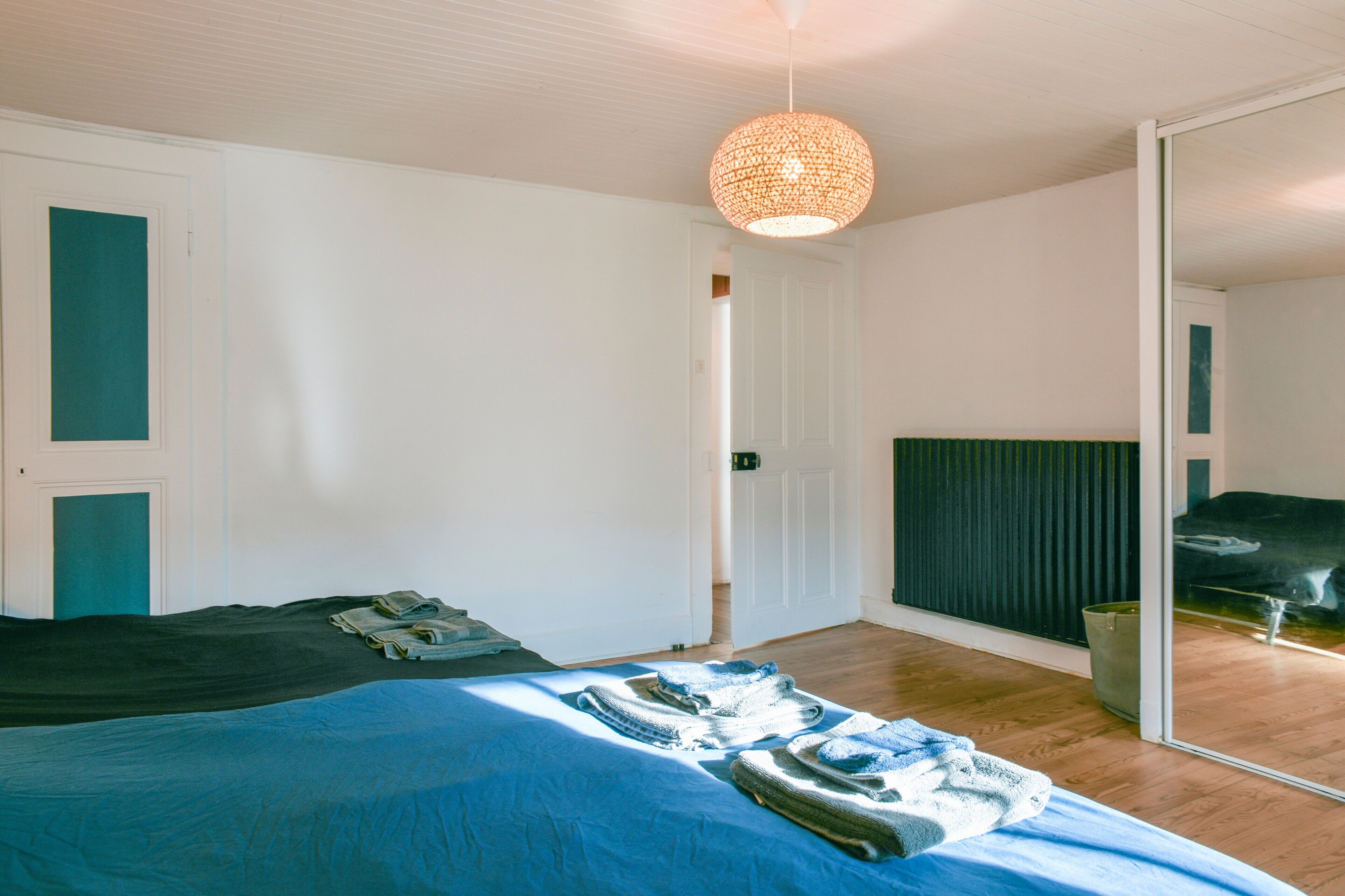 A bedroom with a bed, a mirror, and a hanging light fixture.
