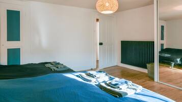 A bedroom with a bed, a mirror, and a hanging light fixture.
