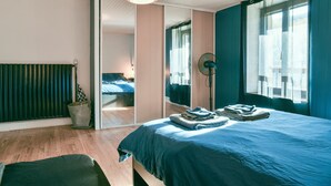 Une chambre à coucher avec un lit, un ventilateur, une fenêtre et une vue sur une autre pièce.