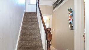 A carpeted staircase with wooden balusters leading to a landing. - Pebbles (Eastbourne)