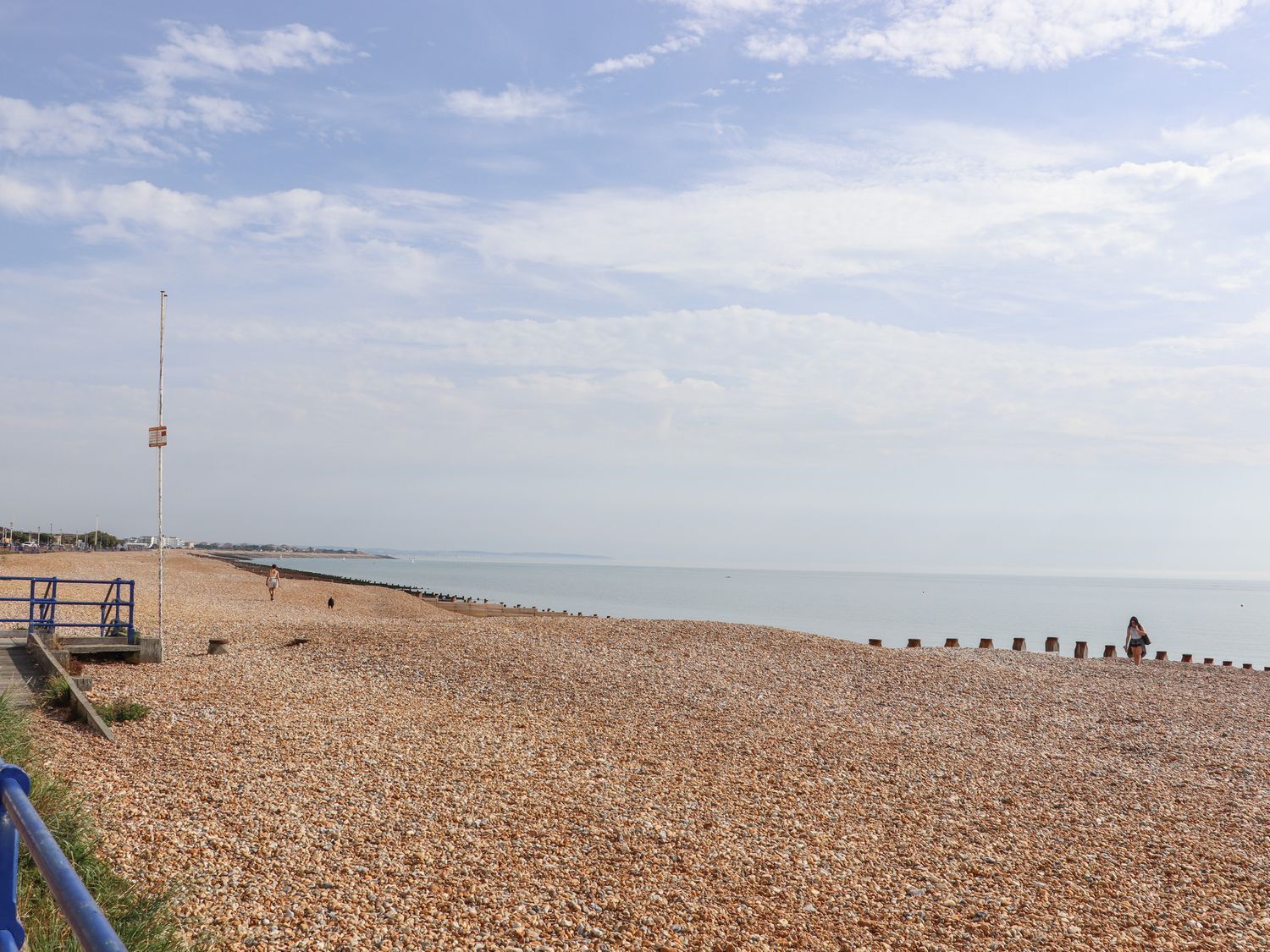 A pebbled beach with a pier and a lifeguard tower.