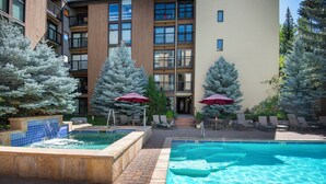 A swimming pool area with two pools, lounge chairs, and red umbrellas. - Pool, Hot Tub, Walk to Gondola | VI111 (Vail)