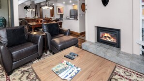 A modern living room with a fireplace, leather sofas, a coffee table with magazines, and a mounted moose head on the wall. - Pool, Hot Tub, Walk to Gondola | VI111 (Vail)