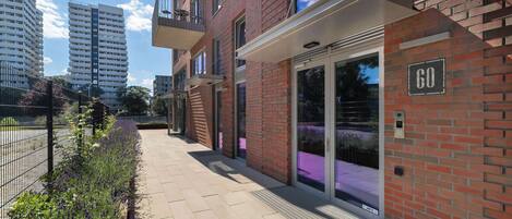 Un immeuble d’appartements moderne avec une façade en briques, de grandes fenêtres et une entrée sécurisée par un portail.