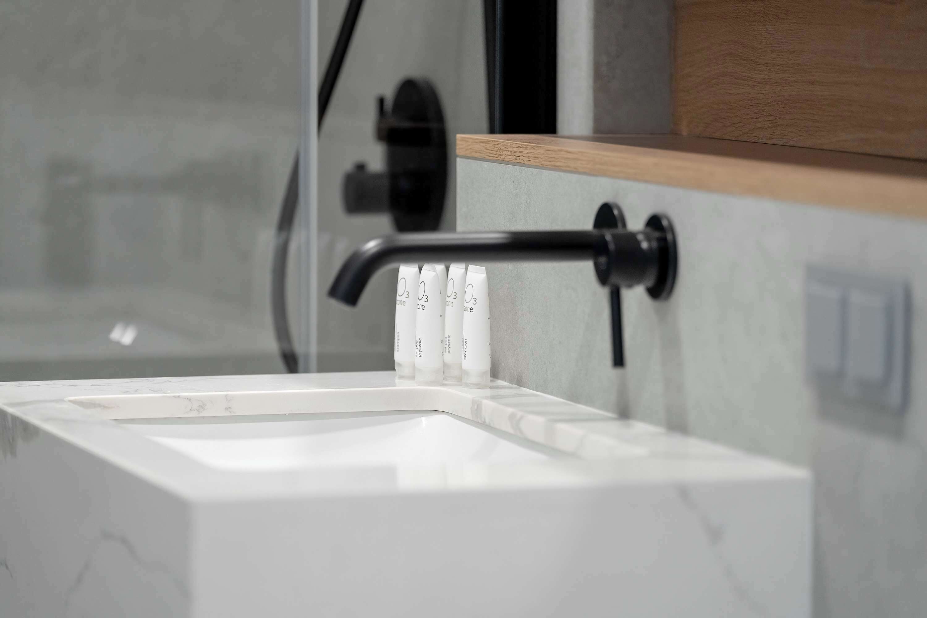 Un baño moderno con un lavamanos blanco, un grifo negro y una encimera de madera.
