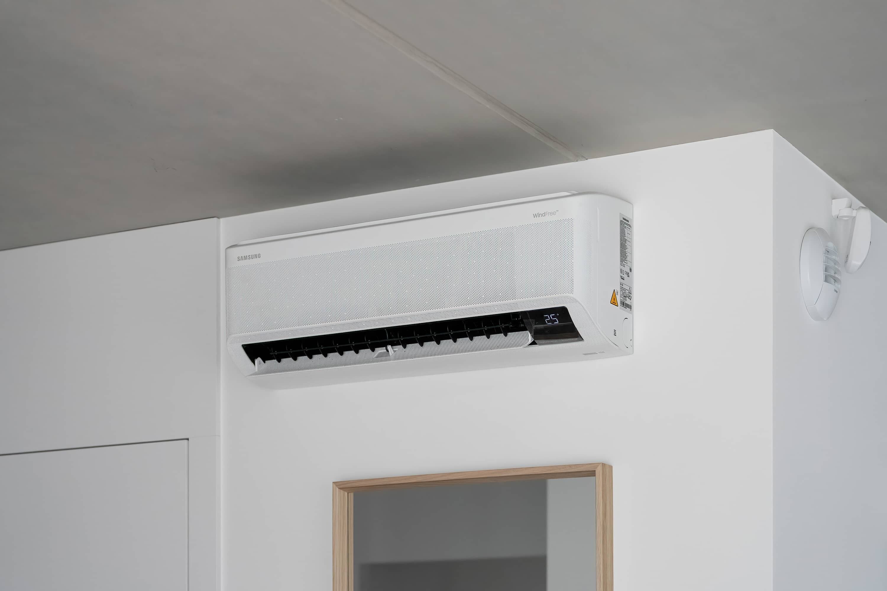 A white air conditioning unit mounted on a wall with a small window below it.