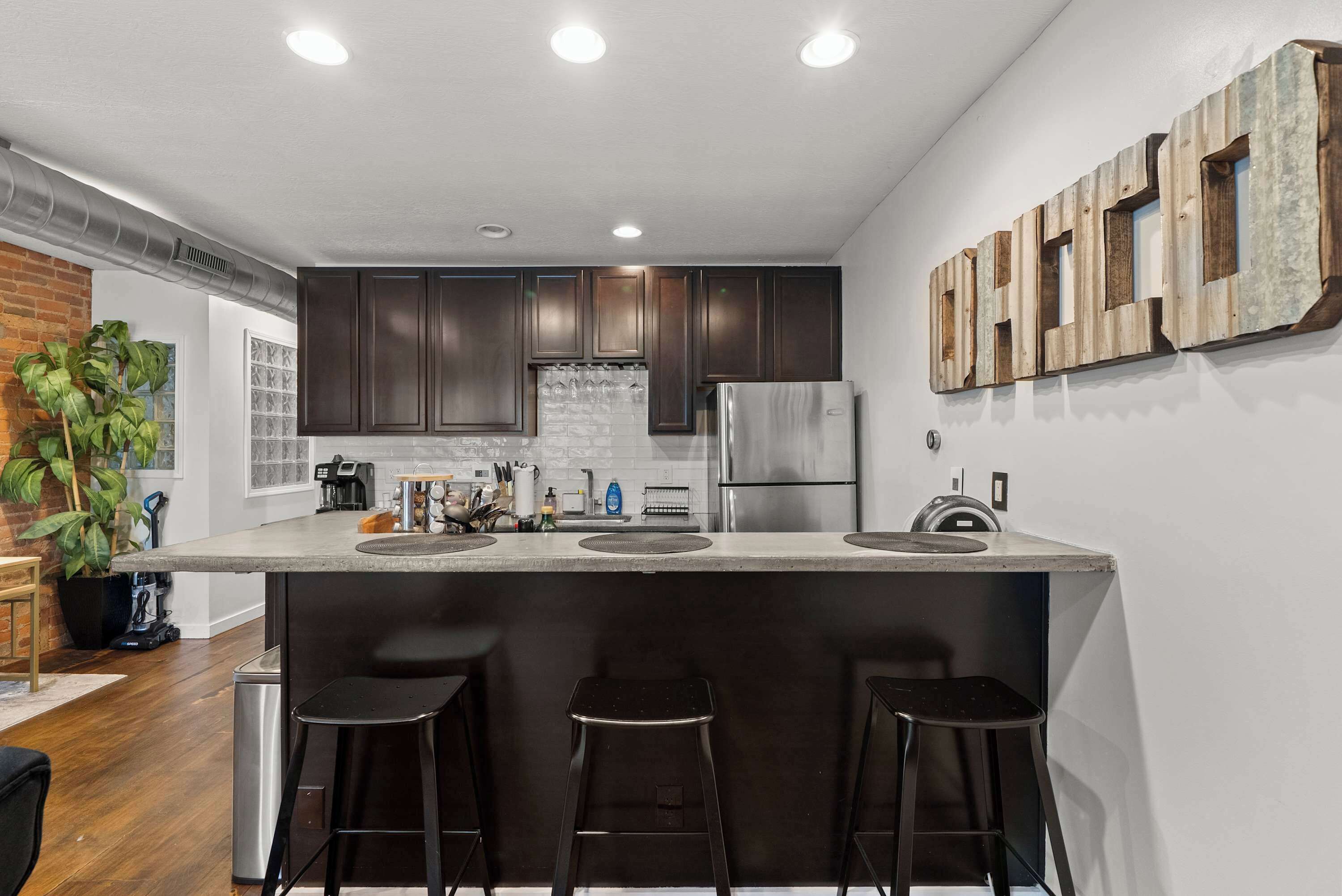 Una cocina moderna con armarios de madera oscura, electrodomésticos de acero inoxidable y una isla central con taburetes.