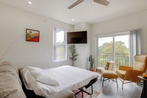 A modern hotel room with a bed, a sofa, a chair, a TV, and large windows offering a view of the outdoors. - Penthouse Condo w/ Rooftop Deck in Philadelphia! (Philadelphia)