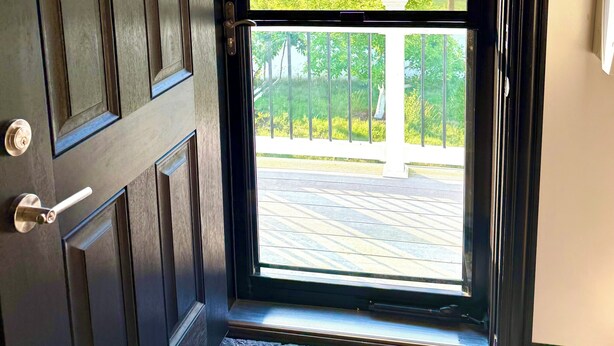 A dark wooden door with a glass panel leading to a balcony with a view of trees and a paved area. - 3BR Retreat in a House 2Floor (Yorkville)