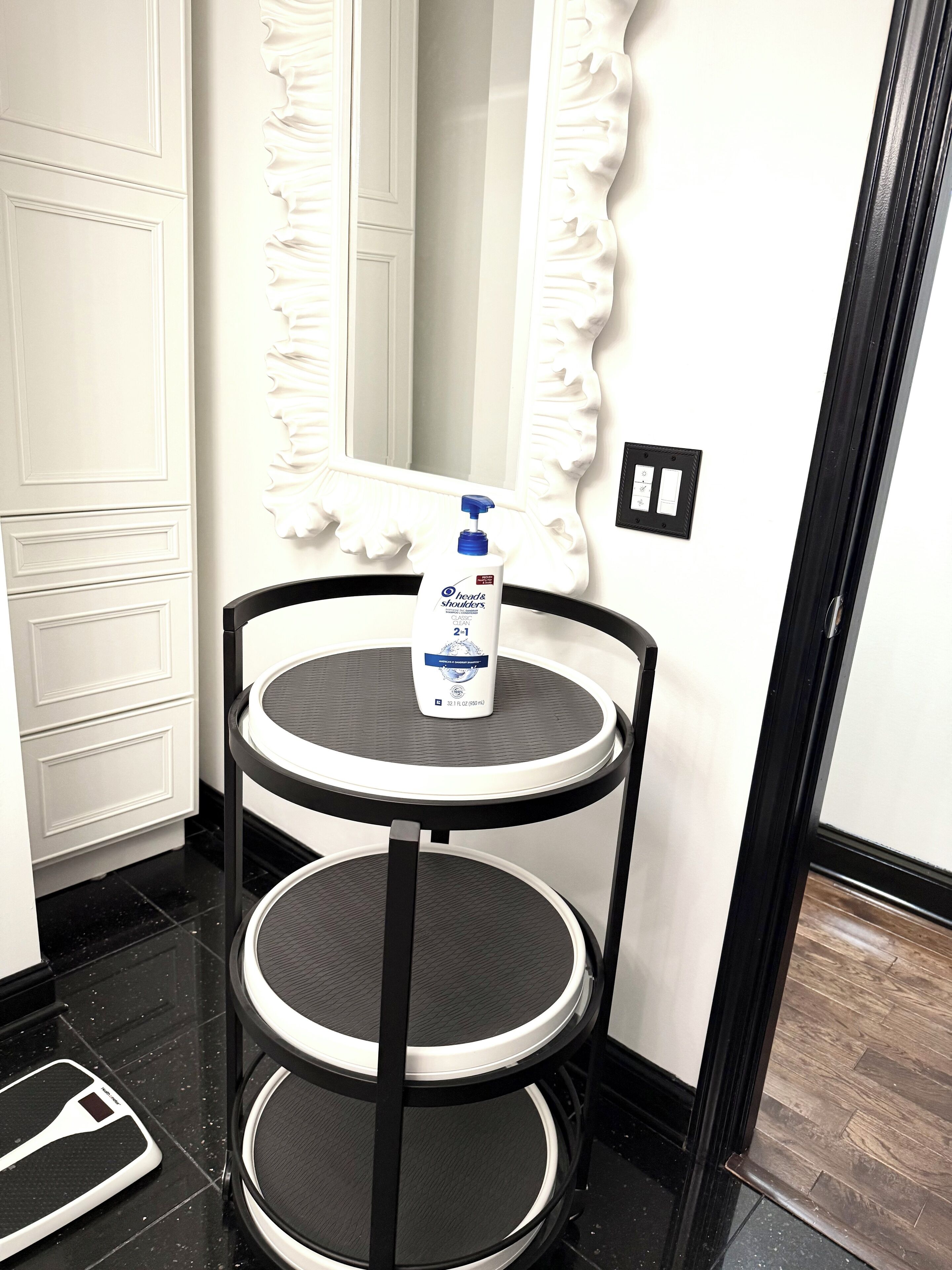 A bathroom with a white vanity, a black and white round table, and a shower area.
